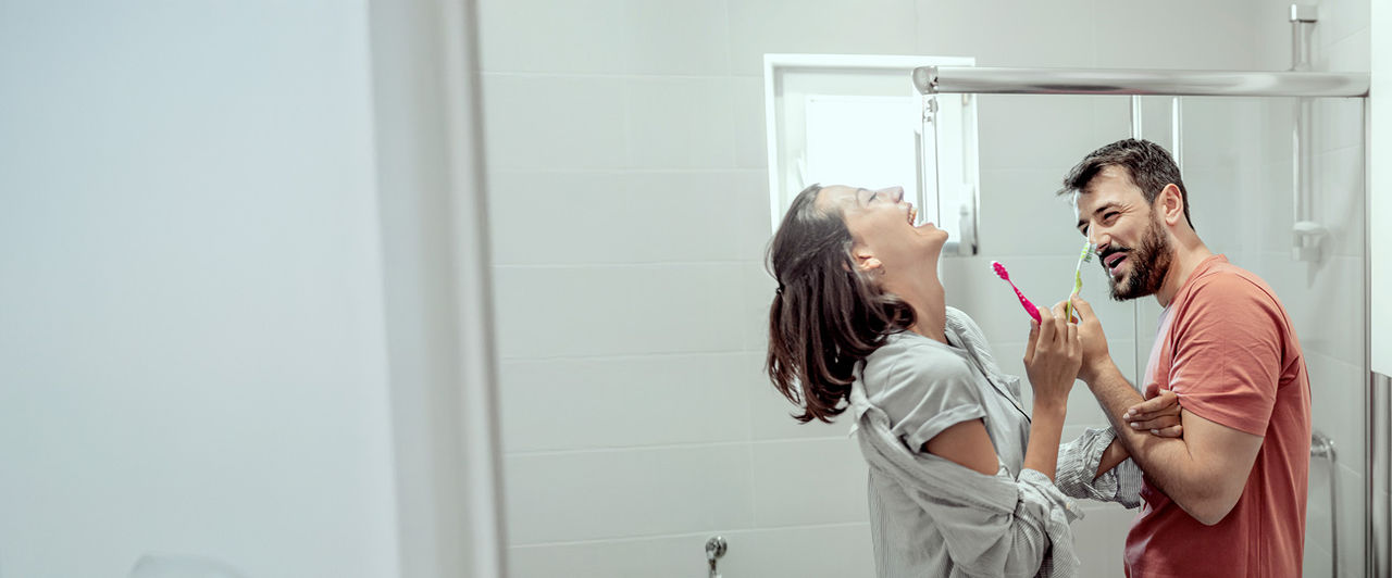 couple brushing teeth together and laughing