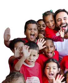 A group of smiling children waving, wearing red Colgate t-shirts, alongside a smiling man in a white shirt